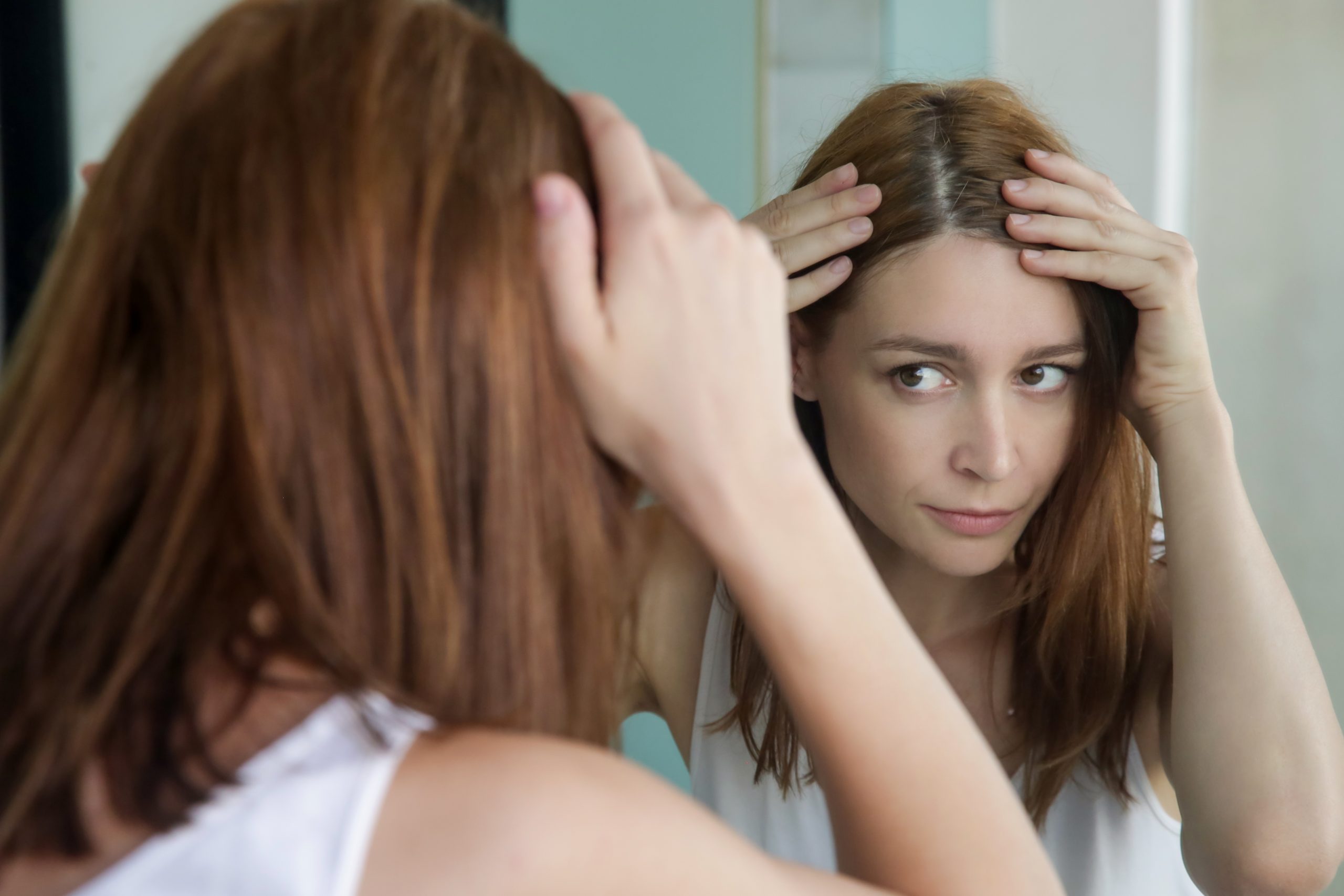 woman checking hair line in mirror